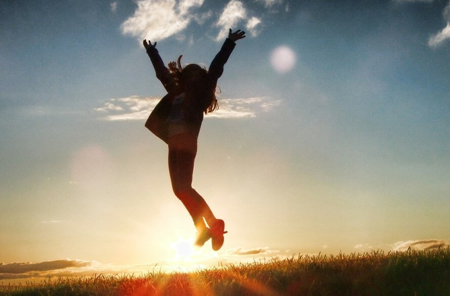 A woman jumping triumphantly in the sunset