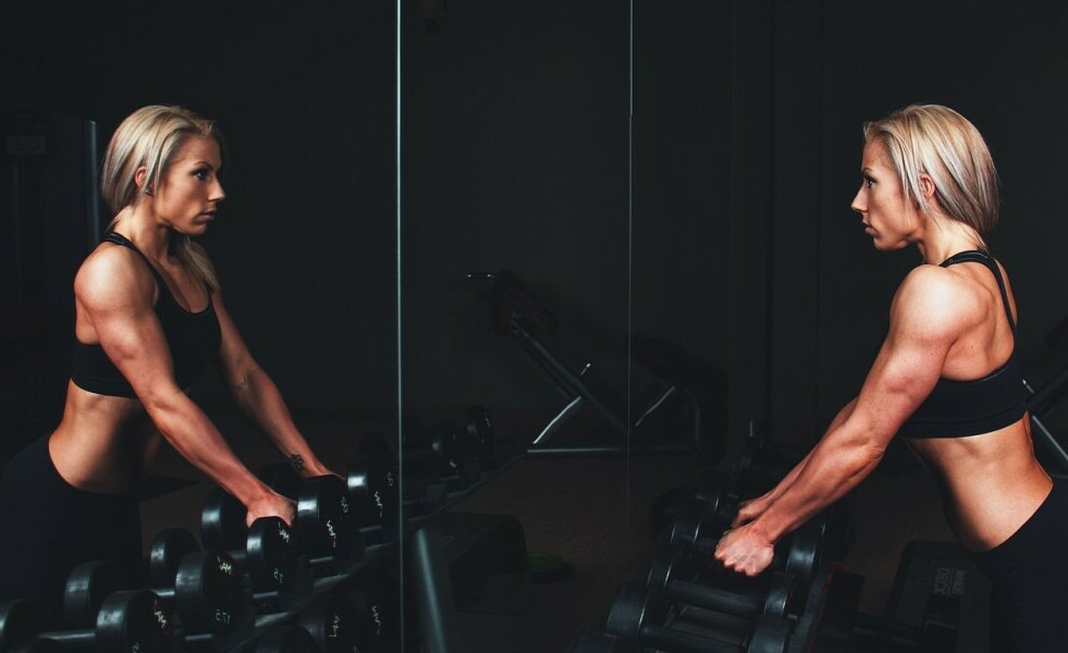 A woman looking at herself in the mirror at the gym